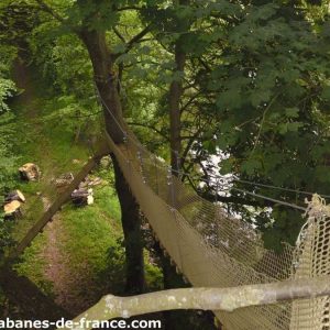 Cabane perchée dans les arbres en Basse-Normandie, entourée de verdure luxuriante.