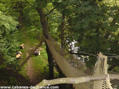 Cabane perchée dans les arbres en Basse-Normandie, entourée de verdure luxuriante.