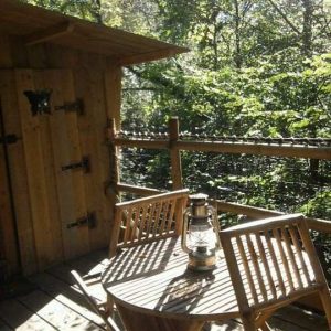 Cabane perchée en Basse-Normandie, avec terrasse en bois et lanternes vintage.