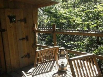 Cabane perchée en Basse-Normandie, avec terrasse en bois et lanternes vintage.