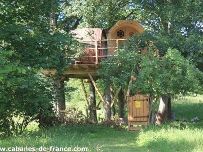 Cabane dans les arbres en Basse-Normandie, perchée entre les feuillages verdoyants.