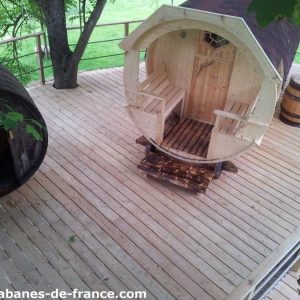 Hébergement insolite en forme de tonneau, situé sur une terrasse en bois.