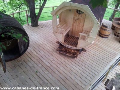 Hébergement insolite en forme de tonneau, situé sur une terrasse en bois.
