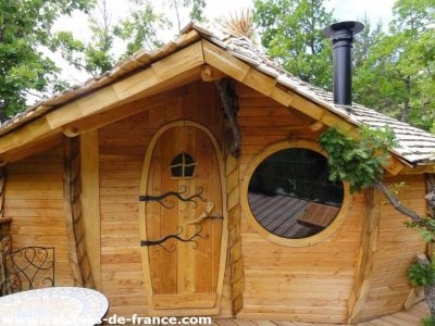 Cabane en bois avec un toit en ardoise et une grande fenêtre ronde, Auvergne-Rhône-Alpes.