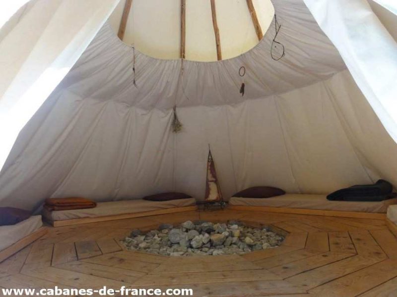 Tente tipi cosy en Auvergne-Rhône-Alpes, avec un espace central en bois et pierres.
