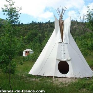 Tipi blanc au milieu de la verdure, offrant une expérience unique en Auvergne-Rhône-Alpes.