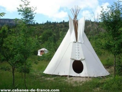Tipi blanc au milieu de la verdure, offrant une expérience unique en Auvergne-Rhône-Alpes.