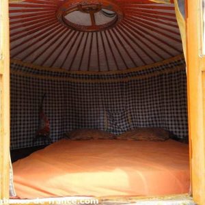 Yourte colorée avec un lit douillet, offrant une expérience unique en Auvergne-Rhône-Alpes.