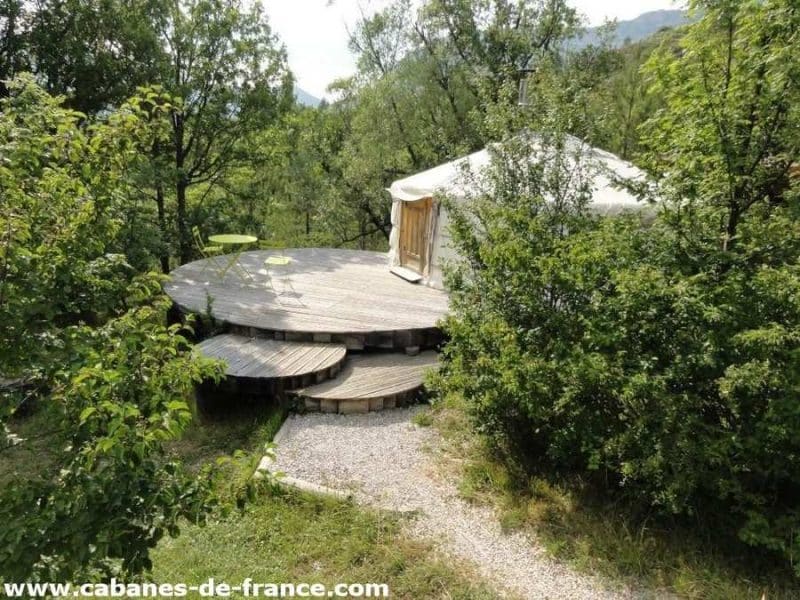 Hébergement insolite : yourte sur plateforme en bois, entourée de verdure luxuriante.