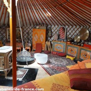 Yourte colorée en Auvergne-Rhône-Alpes, avec un poêle et des décorations artisanales.