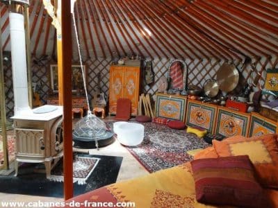 Yourte colorée en Auvergne-Rhône-Alpes, avec un poêle et des décorations artisanales.