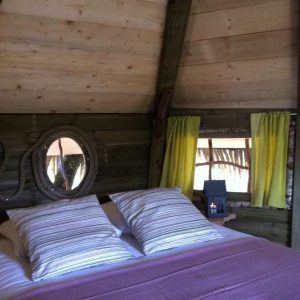 Chalet en bois à Ile-de-France, avec des rideaux jaunes et un lit douillet.