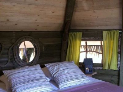 Chalet en bois à Ile-de-France, avec des rideaux jaunes et un lit douillet.