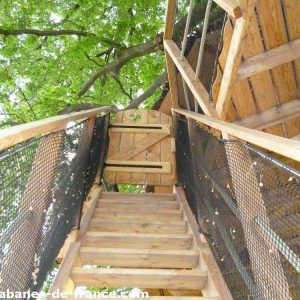 Cabane dans les arbres en Hauts-de-France, accès par un escalier en bois.