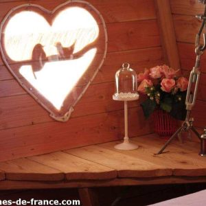 Cabane romantique en Hauts-de-France, avec fenêtre en forme de cœur et fleurs.