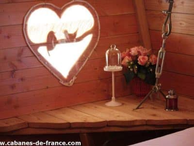 Cabane romantique en Hauts-de-France, avec fenêtre en forme de cœur et fleurs.