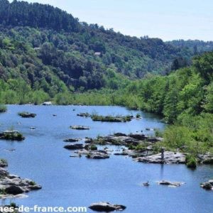 Cabane en bois au bord dune rivière, entourée de verdure luxuriante.