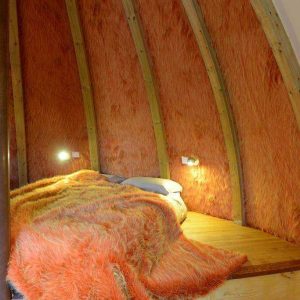 Cabane insolite en Pays de la Loire, intérieur chaleureux avec murs en fourrure orange.