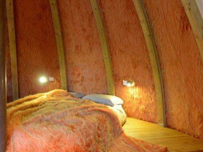 Cabane insolite en Pays de la Loire, intérieur chaleureux avec murs en fourrure orange.