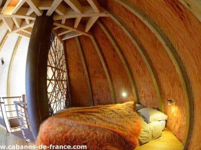 Cabane en bois dans les Pays de la Loire, avec murs en bois chaleureux et lit douillet.