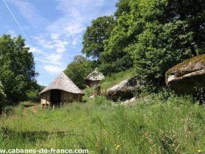 Cabanes en bois au cœur de la nature, entourées de verdure et de rochers.
