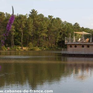 Cabane flottante en Aquitaine, entourée de verdure et reflet sur leau.