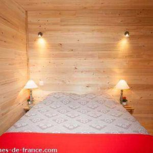 Cabane en bois en Aquitaine, lit douillet avec éclairage chaleureux.