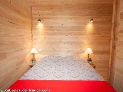 Cabane en bois en Aquitaine, lit douillet avec éclairage chaleureux.