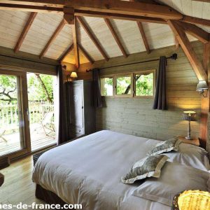 Chalet en bois avec vue sur la nature, lit douillet et ambiance chaleureuse.