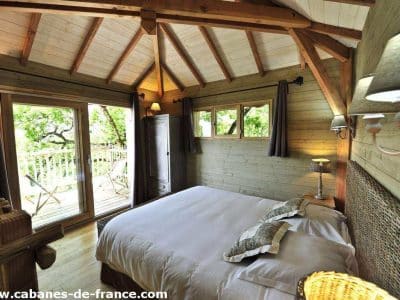 Chalet en bois avec vue sur la nature, lit douillet et ambiance chaleureuse.