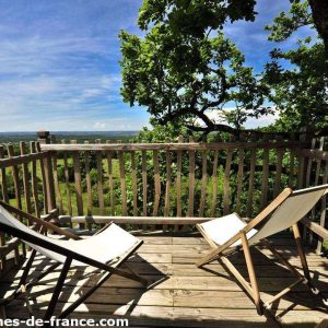 Cabane perchée en Midi-Pyrénées avec terrasse en bois et chaises confortables.