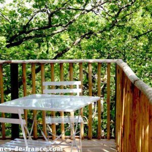 Cabane perchée en Aquitaine avec terrasse en bois entourée de verdure.