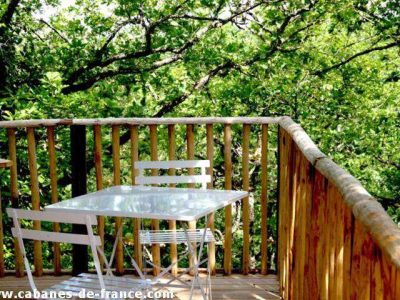 Cabane perchée en Aquitaine avec terrasse en bois entourée de verdure.