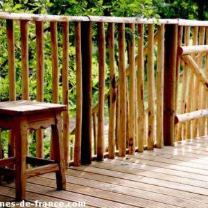 Cabane en bois en Aquitaine avec une terrasse en bois et un tabouret rustique.
