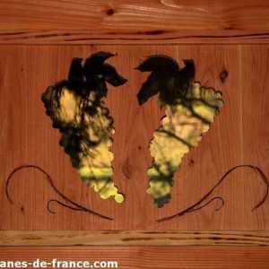 Cabane en bois avec une décoration en métal représentant des grappes de raisin.