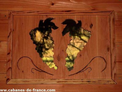 Cabane en bois avec une décoration en métal représentant des grappes de raisin.