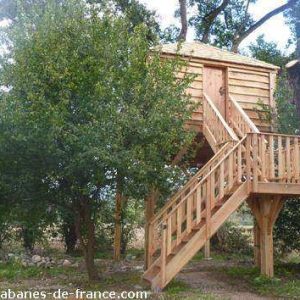 Cabane perchée en bois dans les arbres, entourée de verdure à Midi-Pyrénées.