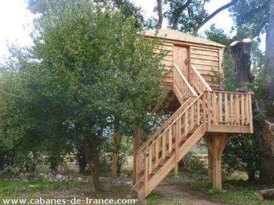 Cabane perchée en bois dans les arbres, entourée de verdure à Midi-Pyrénées.
