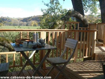 Cabane perchée en Midi-Pyrénées avec terrasse en bois et vue sur la nature.