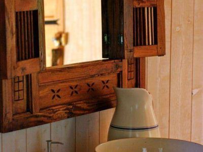 Élégante cabane en bois avec lavabo en céramique et miroir à volets.