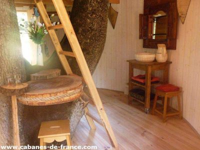 Cabane dans un arbre en Midi-Pyrénées, avec un intérieur en bois chaleureux et décor naturel.