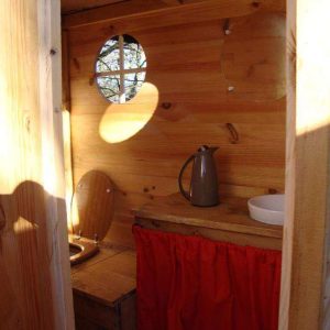 Cabane en bois dans les Midi-Pyrénées, avec un coin cuisine et fenêtres rondes.