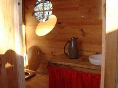 Cabane en bois dans les Midi-Pyrénées, avec un coin cuisine et fenêtres rondes.