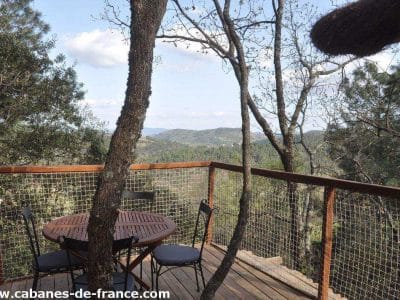 Cabane perchée en bois avec terrasse, vue panoramique sur la forêt en Auvergne-Rhône-Alpes.