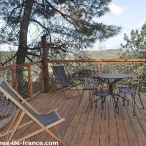 Cabane perchée en Auvergne-Rhône-Alpes avec terrasse en bois et vue dégagée sur la nature.