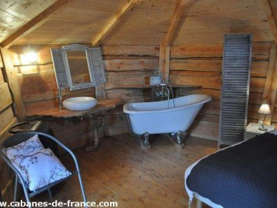 Cabane en bois en Auvergne-Rhône-Alpes avec baignoire sur pattes et décor chaleureux.