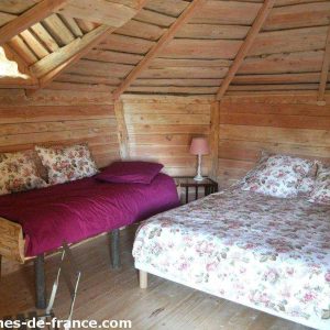Cabane en bois cosy avec lits fleuris, située en Auvergne-Rhône-Alpes.