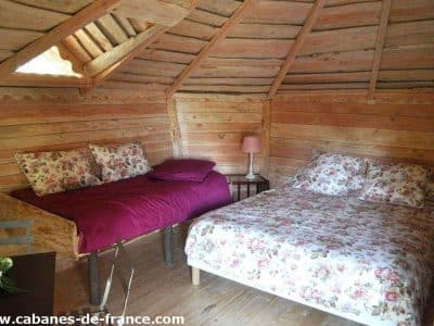 Cabane en bois cosy avec lits fleuris, située en Auvergne-Rhône-Alpes.