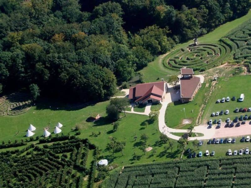 Cabanes en pleine nature avec vue sur un jardin labyrinthique verdoyant.