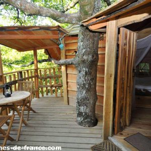 Cabane dans les arbres en Aquitaine, avec terrasse en bois et vue sur la nature.